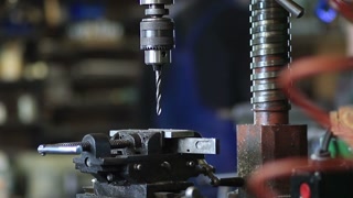 Drilling hole in iron piece with auger in workshop