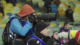 A photographer, photographers with a camera in a stadium during a football match.