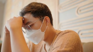 Close-up of Asian man wearing a mask chatting on a smartphone, worrying about his life.